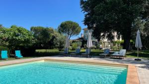 una piscina con sedie e ombrelloni di Maison d'hôtes Le Parc a Labruguière