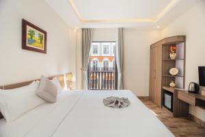- une chambre avec un grand lit blanc et une télévision dans l'établissement Green bay hotel Ha Long, à Hạ Long