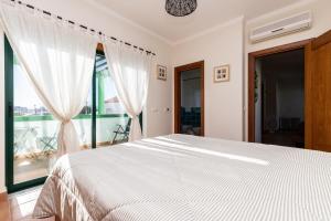 una camera da letto con un letto bianco e una grande finestra di Acoteias do Alto A by Algarvemanta a Manta Rota Altre 37 foto