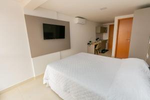 1 dormitorio con 1 cama blanca y TV de pantalla plana en Manaíra Apart Flat en João Pessoa