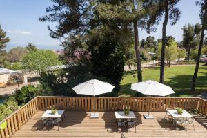 2 mesas y 2 sombrillas en una terraza de madera en Kibbutz Malkiya Travel Hotel, en Malkiyya