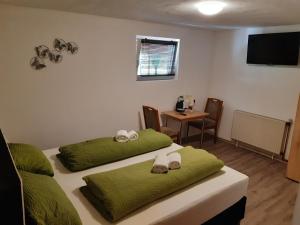 a room with two beds with green sheets and a table at Steakhaus Galgenbach in Werne an der Lippe