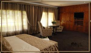 a hotel room with a bed and a table and chairs at Water on Waldrift Guesthouse in Vereeniging
