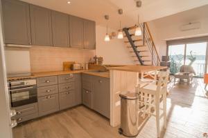 a kitchen with gray cabinets and a wooden counter top at Les Marines du Soleil - Vue Mer in Patrimonio