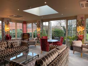 a living room with couches and tables and windows at Park Farm Hotel in Norwich