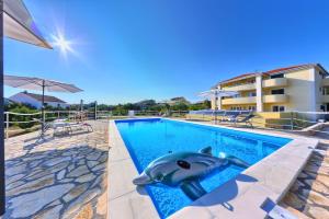a swimming pool with a dolphin in the middle at Apartments CVITA HOLIDAY - Villa NATALI in Rogoznica