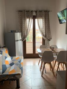 cocina con mesa, sillas y nevera en Bed and Breakfast Dolly en SantʼAntìoco