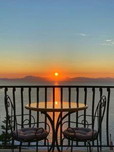 uma mesa e cadeiras numa varanda com um pôr-do-sol em Sea&sky em Praiano