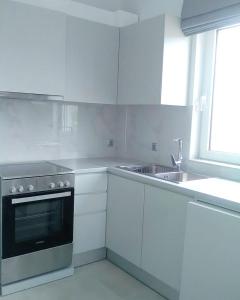 a kitchen with white cabinets and a stove and a sink at Theasis Limnos - 1st floor suite in Agios Ioannis Kaspaka