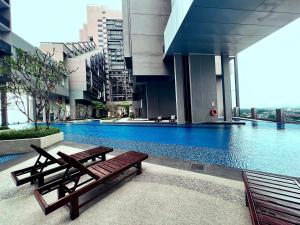 a building with a swimming pool with two wooden benches at Imperio Residences Melaka Malacca in Melaka