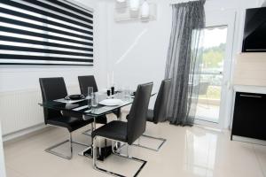 una sala da pranzo con tavolo in vetro e sedie nere di Mistral Luxury Living a Néa Péramos