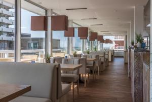 un restaurante con mesas, sillas y ventanas grandes en Hotel Christiansen, en Cuxhaven