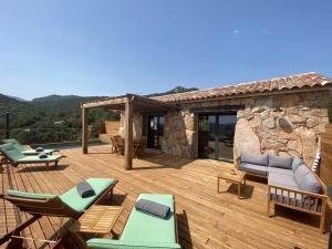 a wooden deck with furniture and a stone building at Bergeries de charme Caselle di Conca in Conca