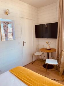 a room with a table and a tv on the wall at Hôtel Le Britannic - centre gare- in Saint Malo