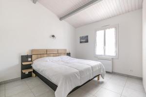 a white bedroom with a large bed in it at Au coeur de l'Ile, appartement lumineux pour quatre personnes in La Guérinière