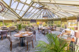 a conservatory with tables and chairs and a glass ceiling at Park Farm Hotel in Norwich +162 photos
