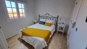 a bedroom with a bed with yellow and white sheets and a window at La Casita del Arco Ático in San Pedro