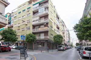 un edificio alto en una calle de la ciudad con coches aparcados en Apartamento Caleta en Granada