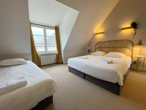 um quarto de hotel com duas camas e uma janela em Maison des fleurs em Saint-Aignan