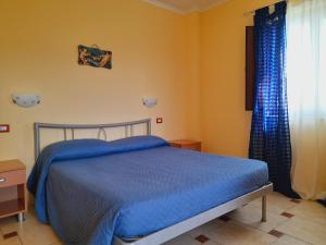 Schlafzimmer mit einem Bett mit blauer Bettwäsche und einem Fenster in der Unterkunft Colle d'Elce in Deliceto