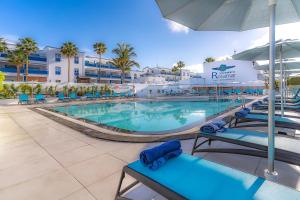 a swimming pool with chairs and an umbrella at a resort at Rosamar Apartamentos in Puerto del Carmen