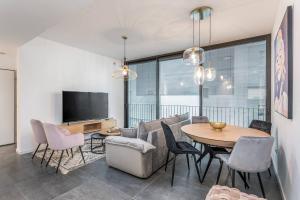 a living room with a table and chairs and a television at Modern and Design 1 BD apt close to the beach in Tel Aviv