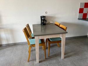 einen Tisch mit vier Stühlen und eine Kaffeemaschine darauf in der Unterkunft Superbe appartement au porte de Montpellier in Juvignac