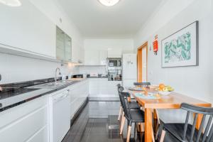 a kitchen with white cabinets and a wooden table and chairs at Jardim do Jasmineiro in Funchal