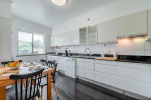 a kitchen with white cabinets and a table with chairs at Jardim do Jasmineiro in Funchal