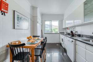 a kitchen with a wooden table and chairs in a room at Jardim do Jasmineiro in Funchal