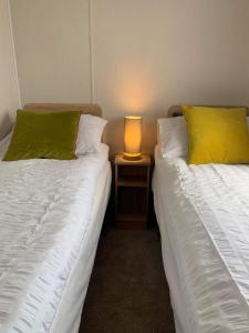 two beds in a room with a lamp on a table at Skegness,North shore holiday park , new 8 berth caravan for rent in Skegness