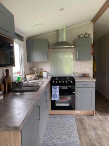 a kitchen with white cabinets and a stove top oven at Skegness,North shore holiday park , new 8 berth caravan for rent in Skegness