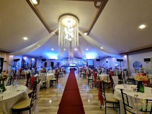 un salón de banquetes con mesas blancas y una lámpara de araña en Buddha Resort by Cocotel, en Bugallon