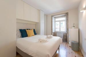 ein Schlafzimmer mit einem großen weißen Bett mit Handtüchern darauf in der Unterkunft Duplex Wonder In Sé W/ Patio by LovelyStay in Porto