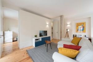 ein Wohnzimmer mit einem weißen Sofa und einem TV in der Unterkunft Duplex Wonder In Sé W/ Patio by LovelyStay in Porto