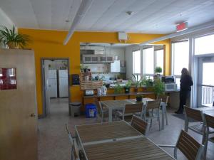a person standing in a kitchen with tables and chairs at Auberge La Petite École de Forillon in Gaspé