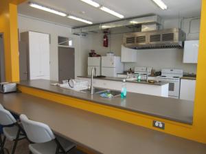 a large kitchen with a counter and chairs in it at Auberge La Petite École de Forillon in Gaspé