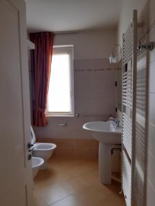 een badkamer met 2 wastafels, een toilet en een raam bij Casa Marì in Garda