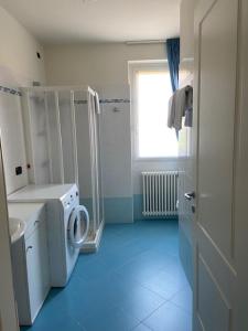 een badkamer met een wasmachine en een raam bij Casa Marì in Garda