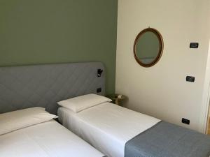 2 bedden in een kleine kamer met een spiegel bij Casa Marì in Garda