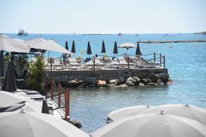 a dock with chairs and umbrellas in the water at Royal Antibes - Luxury Hotel, Résidence, Beach & Spa in Antibes