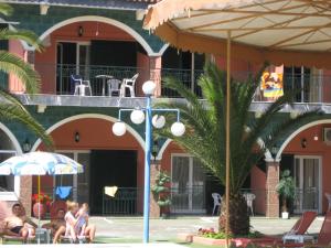 a group of people sitting under an umbrella in front of a building at Villa Magdalena studios in Ágios Ioánnis