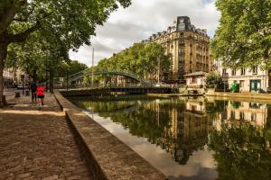 a river in a city with a bridge and a building at Hotel Avalon Paris Gare du Nord in Paris