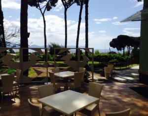 un patio con mesas, sillas y palmeras en Al Corbezzolo, en Torre del Greco