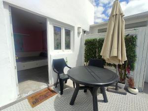 una mesa, sillas y una sombrilla en el patio en Sweet&Wine Apt with terrace by Flamingo House en Arrecife