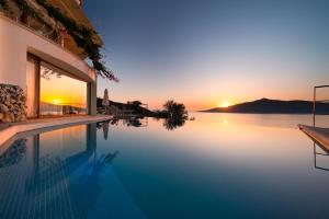 a swimming pool with the sunset in the background at Hotel Villa Mahal in Kalkan