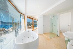 a white bathroom with a tub and a sink at Hotel Villa Mahal in Kalkan