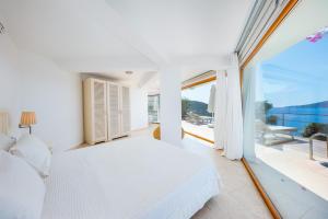 a bedroom with a white bed and a large window at Hotel Villa Mahal in Kalkan