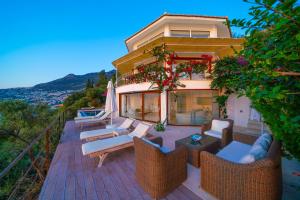 a house with a deck with chairs and an umbrella at Hotel Villa Mahal in Kalkan