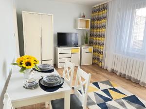 een woonkamer met een tafel en stoelen en een keuken bij Kawalerka SŁONECZNA osiedle DOBRZEC in Kalisz